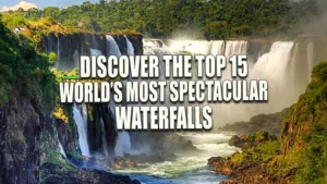 View of Iguazu Falls with voluminous water cascading down multiple lush green cliffs, creating a misty spray, under a clear blue sky.