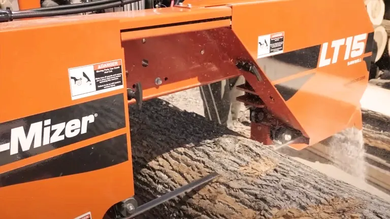 Wood-Mizer LT15 sawmill in action. The sawmill, painted in vibrant orange with a black stripe, is cutting through a large log. The background appears to be a workshop or lumber yard, with the log being transformed into planks. The image succinctly captures the essence of the sawmill’s functionality and purpose.