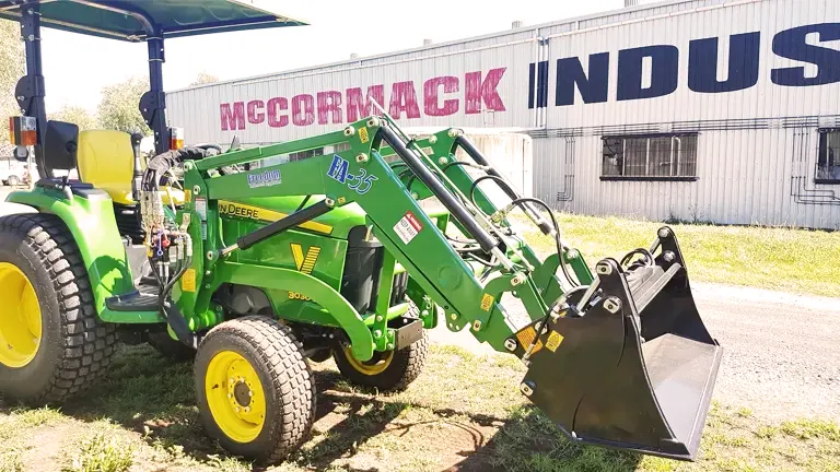 Green John Deere tractor with a front loader parked in front of McCormack Industries.