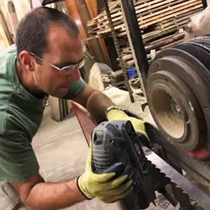 A person sharpening a large circular sawmill blade