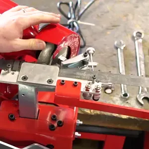 Person adjusting a red sawmill blade with wrenches