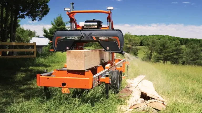 LumberPro HD36V2 sawmill in a wooded area with a tractor in the background.
