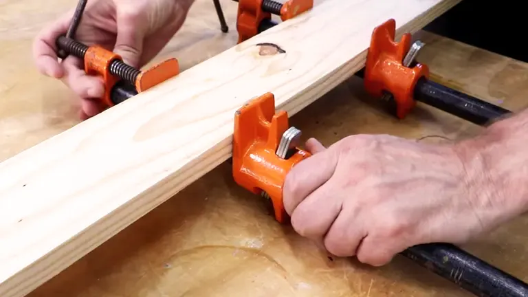 Orange clamps securing wooden boards.