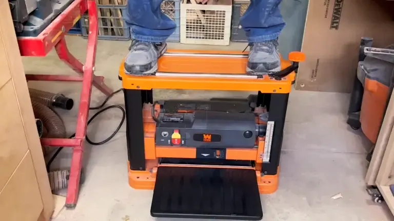 Person standing on an orange and black WEN 6552T Benchtop Planer in a workshop