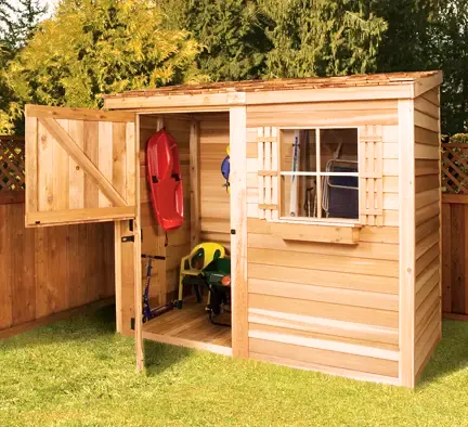Wooden storage shed with open doors revealing stored items like a kayak and gardening tools, situated in a backyard.