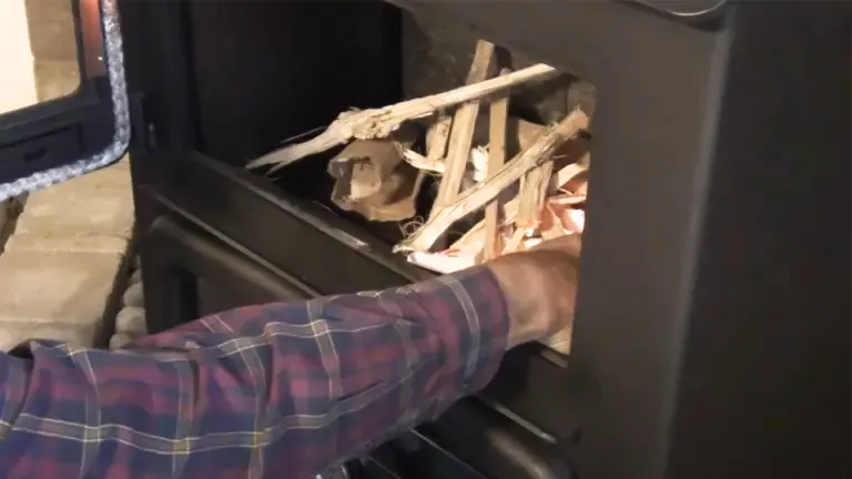 Person loading firewood into a black wood stove.