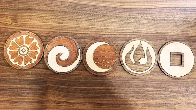 Wooden coasters with natural and geometric designs on a wooden surface.
