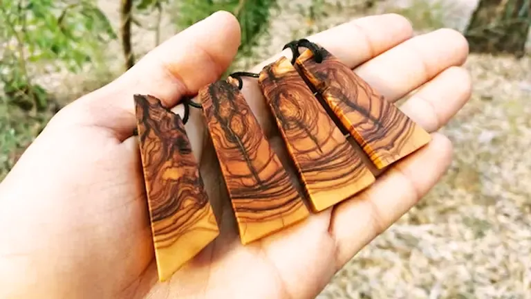 Four wooden pendants with varied grain patterns held in a hand.
