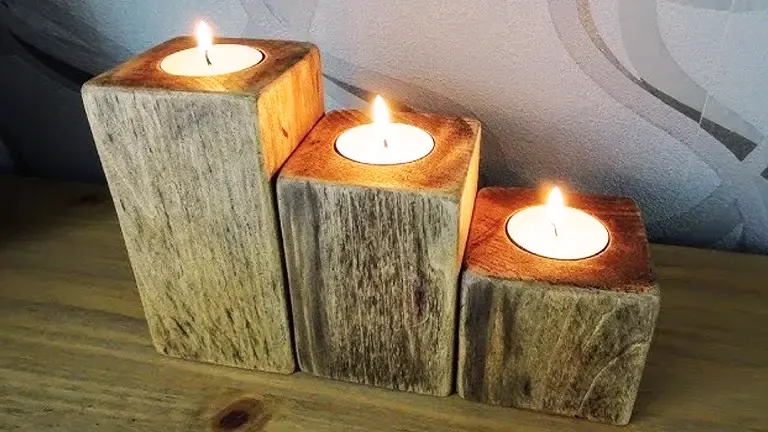 Three wooden blocks with candles on top on a wooden surface.
