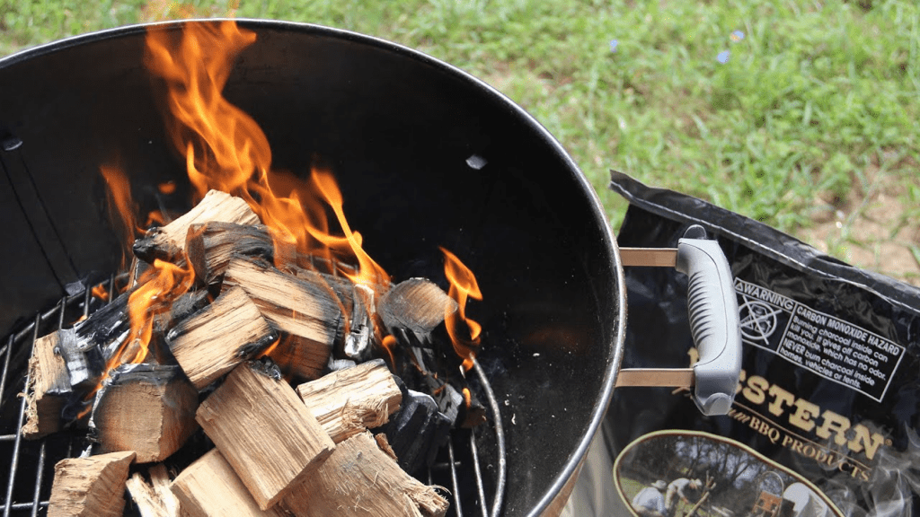 Burning sawmill off cuts in a barbecue grill with a bag of STERN BBQ PRODUCTS to the side.
