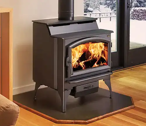 Indoor Lopi Liberty wood stove with burning fire, near a window showing snowy outdoors.