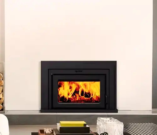 Black Supreme Fusion 18 Wood Burning Insert with visible flames, set in a white wall.
