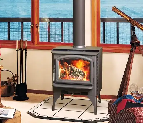 Lopi Answer wood stove with fire, beside telescope and ocean-view windows.