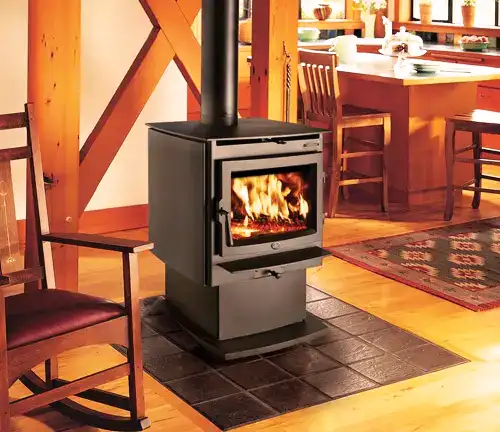 Lopi Evergreen wood stove with fire, in a cozy home interior with wooden chair and open kitchen.