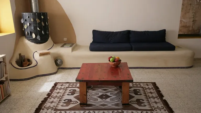 A rocket mass heater Living room with a blue couch, a red coffee table, and a patterned rug.