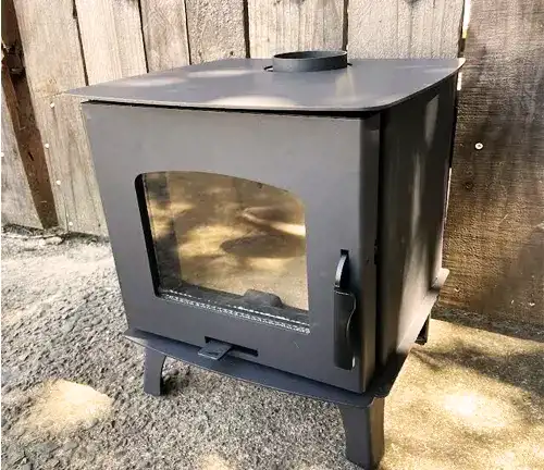 Compact Capybara Mini Wood RV Stove with a glass door, placed outdoors