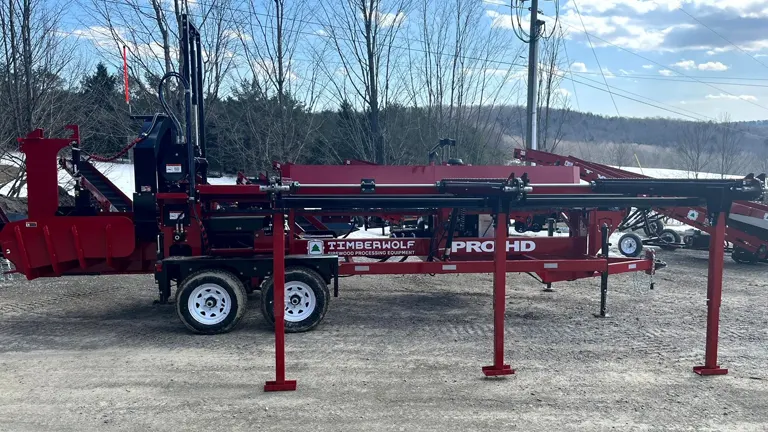 red Timberwolf Pro HD log processor on a trailer with a blue sky and trees in the background.