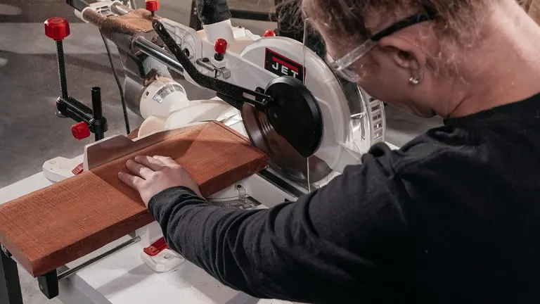 Person using JET JMS-10X 707210 10-Inch Dual-Bevel Compound Miter Saw on a wooden plank