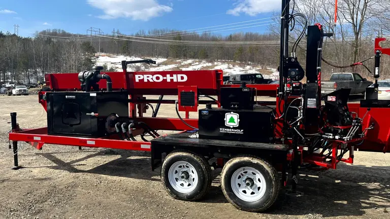 red and black trailer with a PRO-HD label, parked in a dirt lot with various equipment on it.