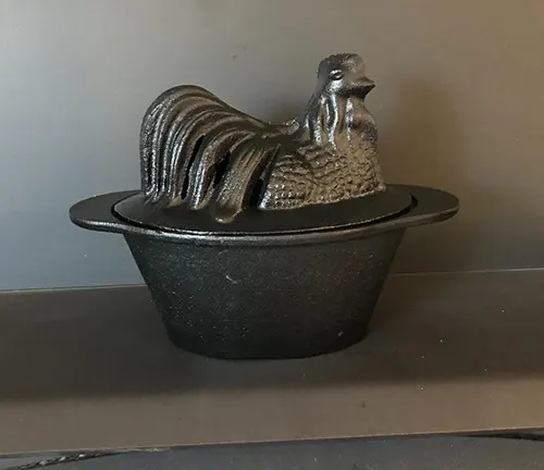 Black cast iron rooster-shaped dish on a gray background.