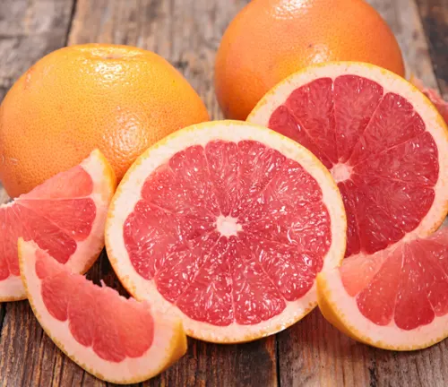 Group of Citrus paradisi (grapefruits), both whole and sliced, on a weathered wooden surface