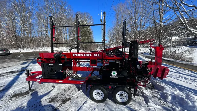 red and black firewood processor, a PRO HD XL model, on a snowy road with bare trees in the background.