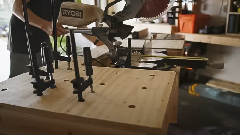 Person using a Ryobi miter saw to build a miter saw station on a wooden workbench in a workshop