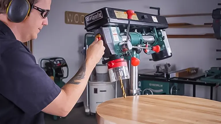 Person using a Grizzly G7945 Benchtop Radial Drill with a red safety switch in a workshop.