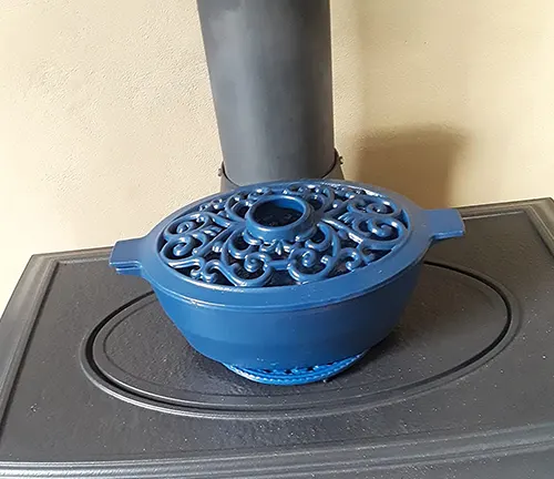 Blue cast iron humidifier on a black wood stove.