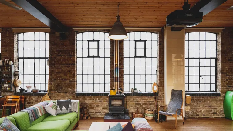 Living room with a wood burning stove, brick walls, and city view.