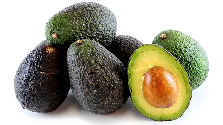 Group of Hass avocados, one cut open to reveal the pit
