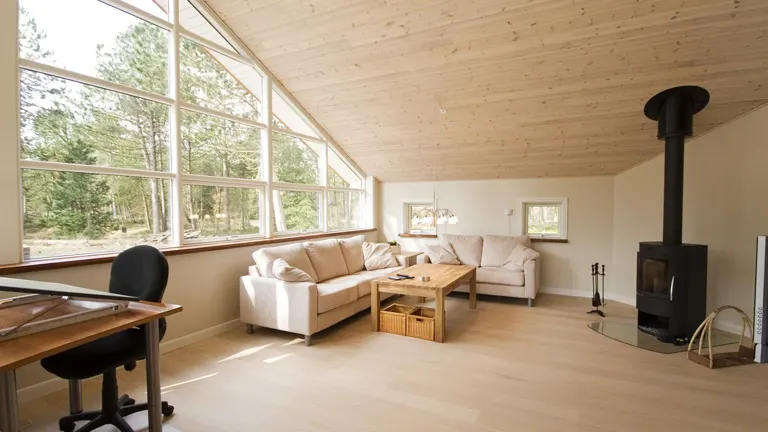Modern living room with a large window and wooden ceiling.
