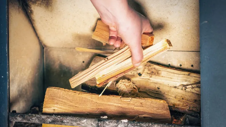 Hand feeding wood to a stove.