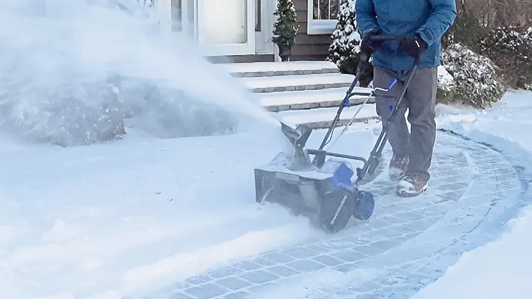 Person using Snow Joe 24V-X2-SB18-TV1 24-Volt IONMAX Snow Blower to clear a snowy sidewalk