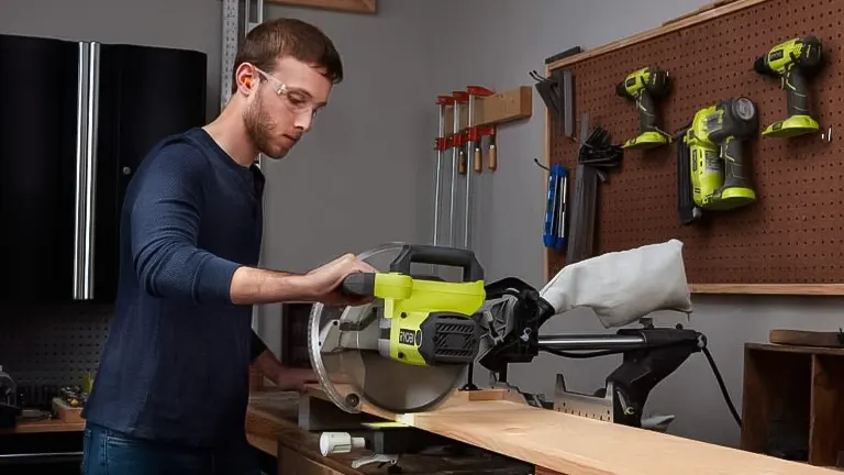 Person using a green and black Ryobi TSS103 10” Sliding Compound Miter Saw in a workshop