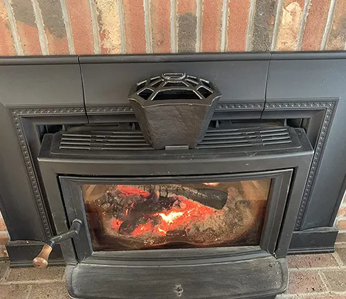 Fireplace with a cast iron pot on top and burning wood inside.