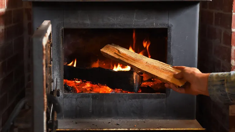 Adding log to wood stove.