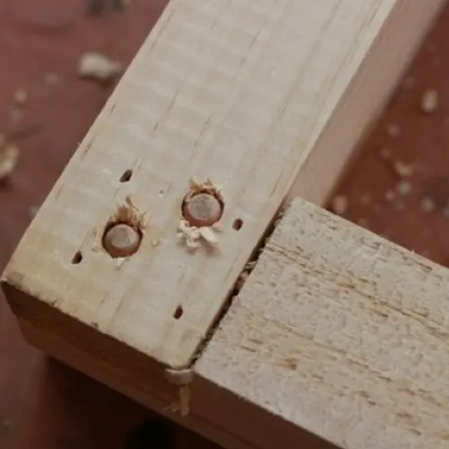 Close up of a wooden dowel joint with two holes and shavings
