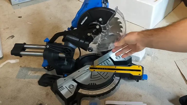 Mastercraft ZP15 10” Single-Bevel Sliding Compound Miter Saw with Laser on a workbench, with a hand reaching for it