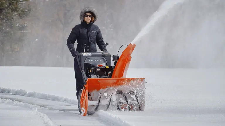 Person using a snowblower to clear a path in the snow.