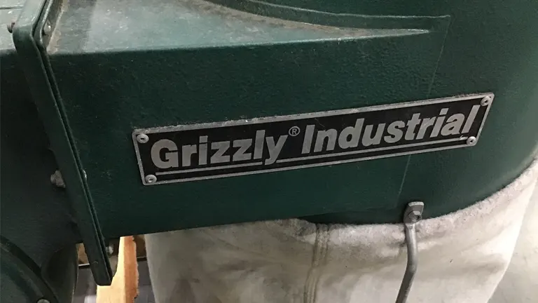 Close up of Grizzly Industrial dust collector with logo and green body.