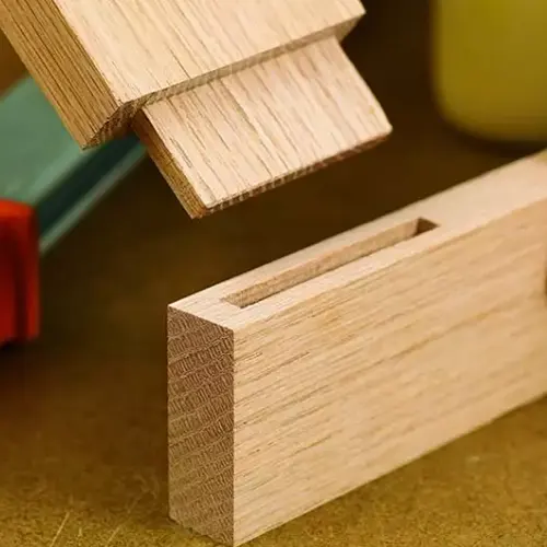 Close up of a rabbet joint in wood, with a green and red background