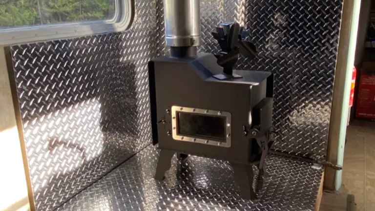 Black wood stove in a room with diamond plate walls.