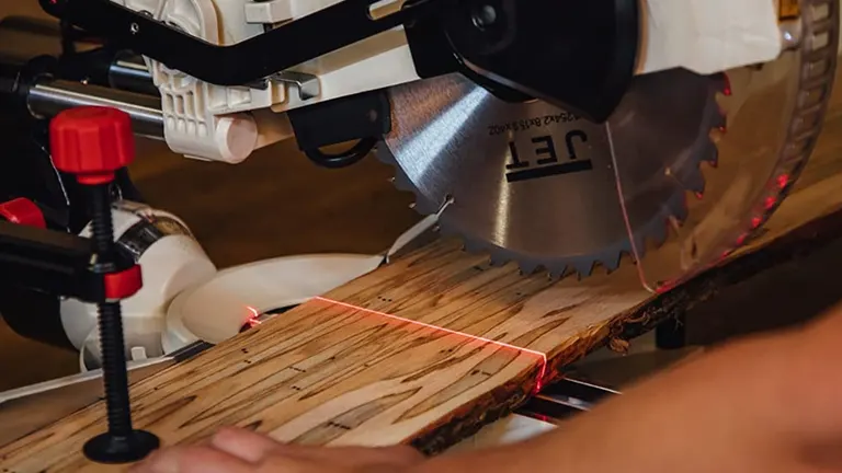 Person using a JET JMS-12X 707212 12-inch dual-bevel compound miter saw to cut a piece of wood