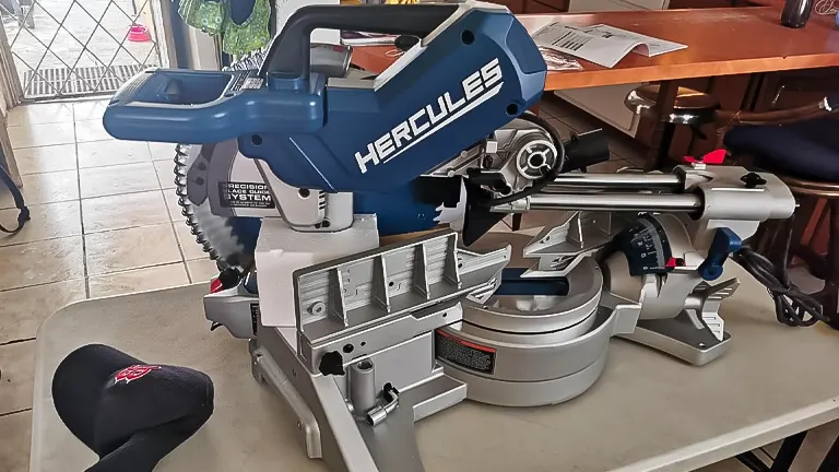 Hercules HE74 12" Dual-Bevel Sliding Compound Miter Saw with Precision LED Shadow Guide on a table with a baseball cap