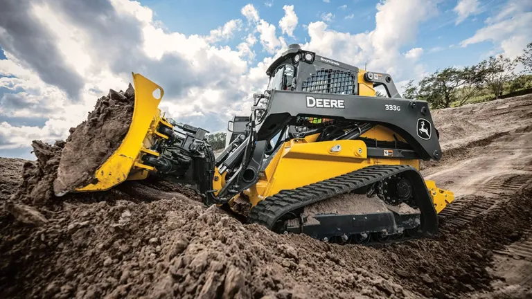 Yellow and black John Deere 333G compact track loader moving dirt on a construction site.