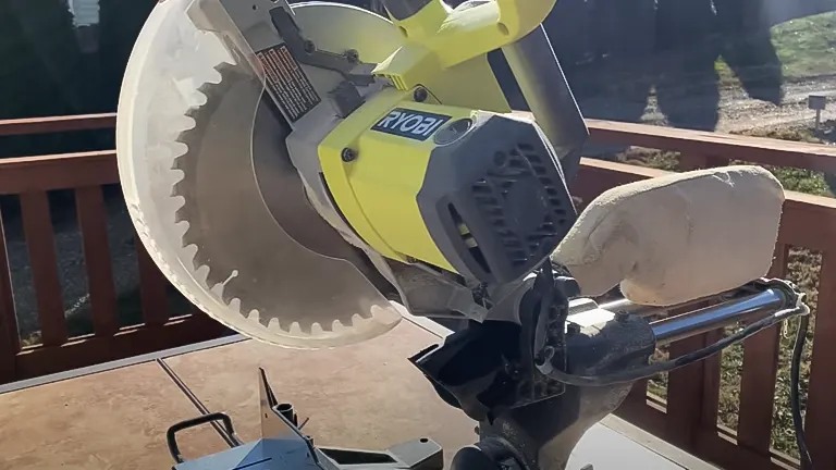 Yellow and black Ryobi TSS103 10” Sliding Compound Miter Saw resting on a wooden deck