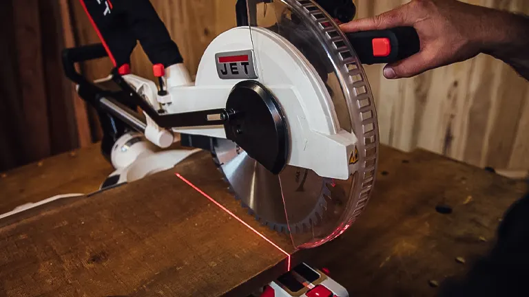 Person using a JET JMS-12X 707212 12-inch dual-bevel compound miter saw to cut a piece of wood