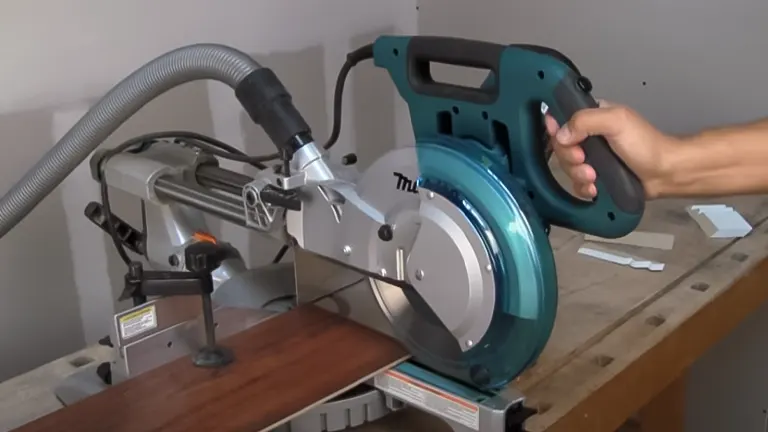 Green and silver Makita LS1018 10” Dual Slide Compound Miter Saw on a workbench with a hand holding the handle