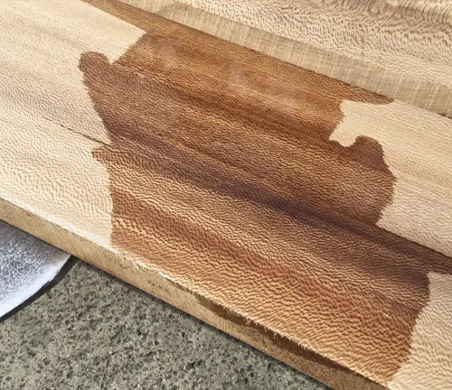 Close up of a wooden bench with a dark stain on it.